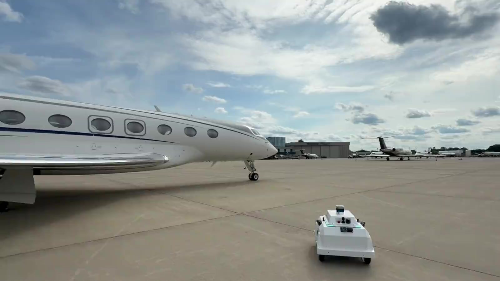 Airtrek wingwalking robots beside a business jet on the ramp, and holding position as a G500 turns